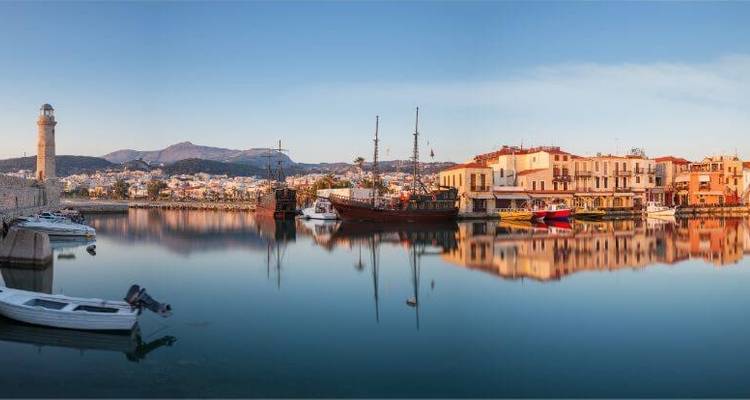 Panoramisch uitzicht op een haven met boten die reflecteren op kalm water.