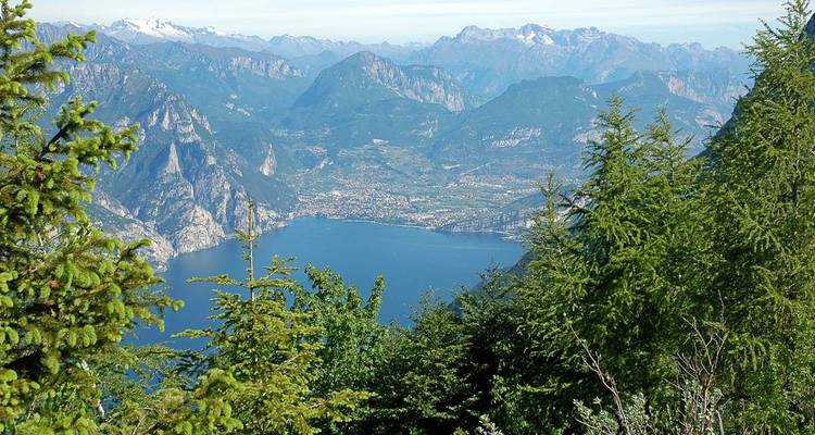 Point de vue surélevé du lac de Garde d'un bleu profond, entouré de pics boisés.