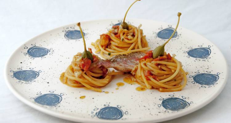 Künstlerischer Teller mit Spaghetti-Nestern, Kapernbeeren und Fischgarnitur