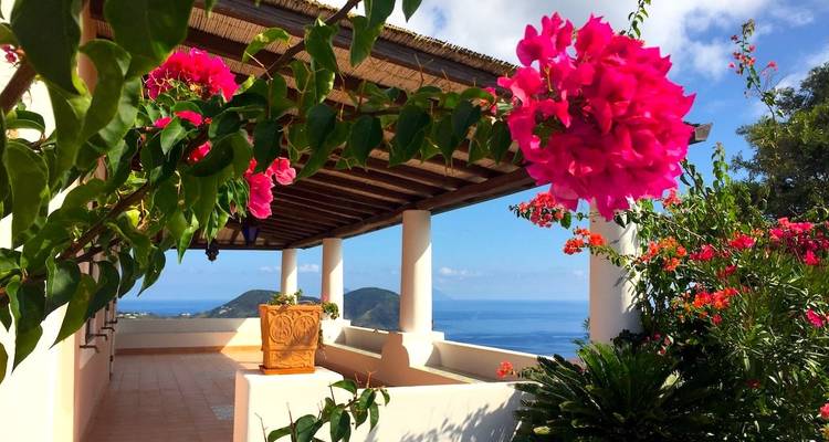 Überdachte Terrasse, geschmückt mit leuchtender Bougainvillea mit Meerblick auf den Äolischen Inseln.