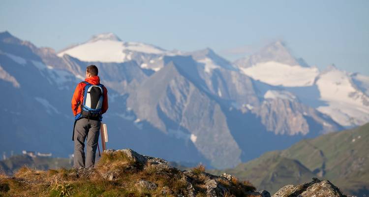 Wanderer mit Rucksack auf Berg mit Blick auf schneebedeckte Gipfel.