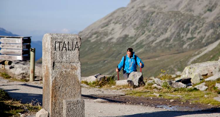 Steingrenzmarkierung mit 'Italia' beschriftet und Wanderer.