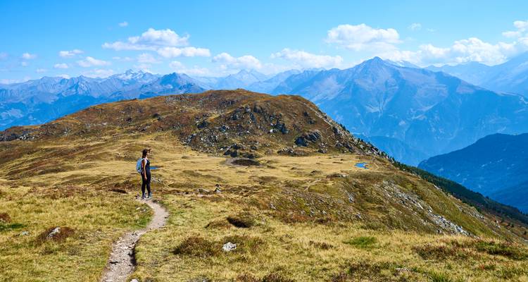 Wanderer auf einem Bergpfad mit entfernten schneebedeckten Gipfeln.