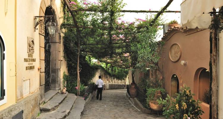 Kopfsteinpflasterstraße mit Bäumen und einer gehenden Person.
