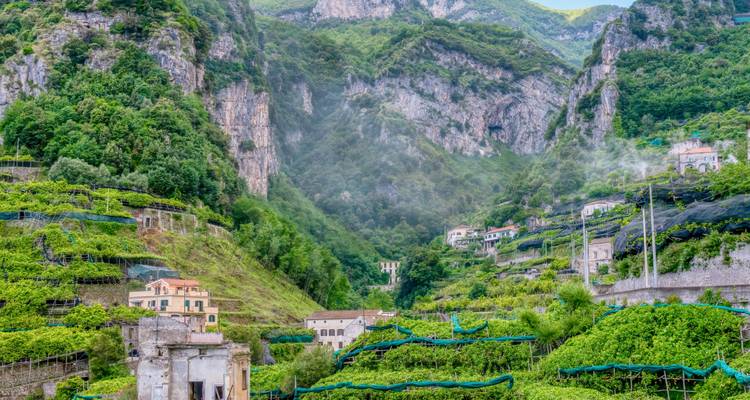 Des vignobles en terrasses luxuriants et des maisons dispersées sur les flancs abrupts et verdoyants de montagnes dans une vallée italienne pittoresque.