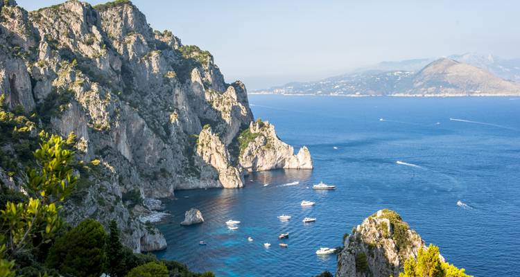 Felsige Küstenklippen mit Blick auf das Meer mit kleinen Booten.