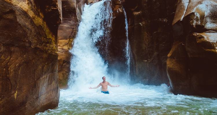 Homme debout sous une cascade.