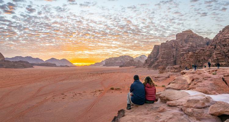 Couple sitting on a rock watching the sunset in a desert landscape.