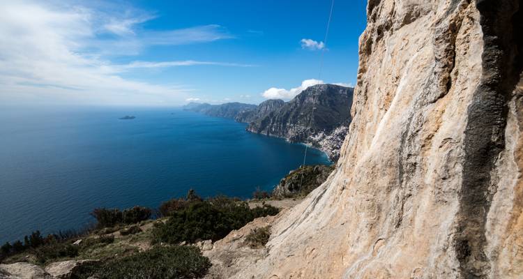 Vue côtière depuis un sentier rocheux escarpé de la côte amalfitaine.
