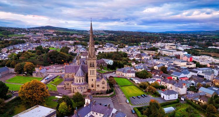 Scenic town with a tall spire surrounded by rolling hills.