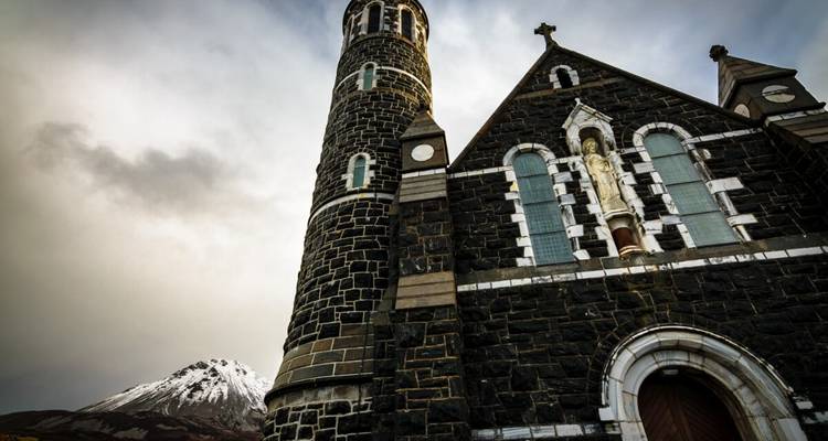 Église historique en pierre avec une montagne en arrière-plan.