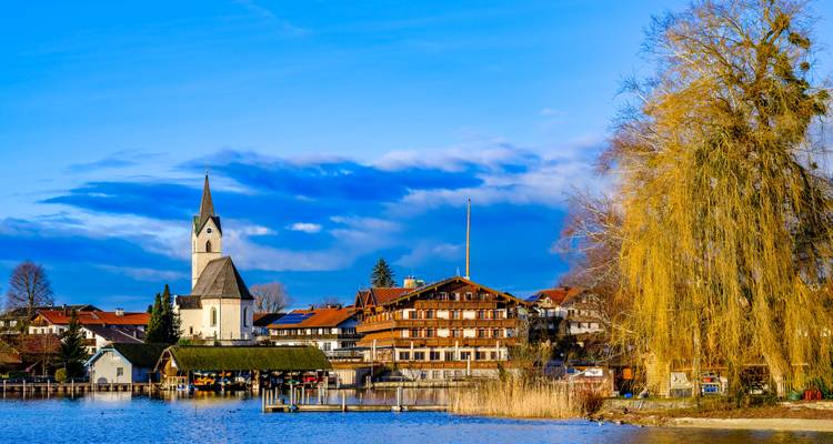 Village au bord du lac avec église et bâtiments traditionnels.