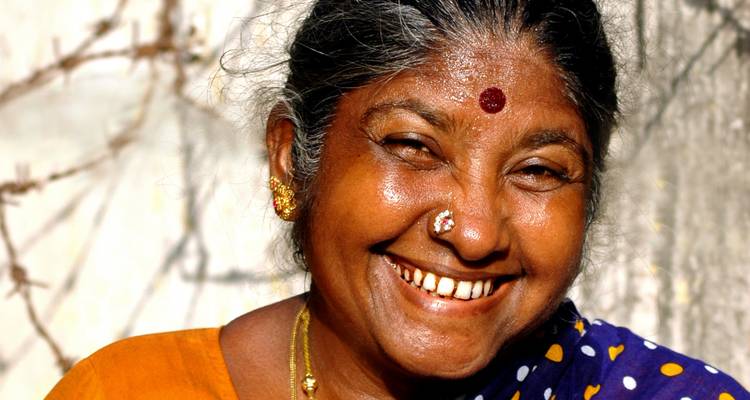 Glimlachende vrouw in kleurrijke traditionele kleding.