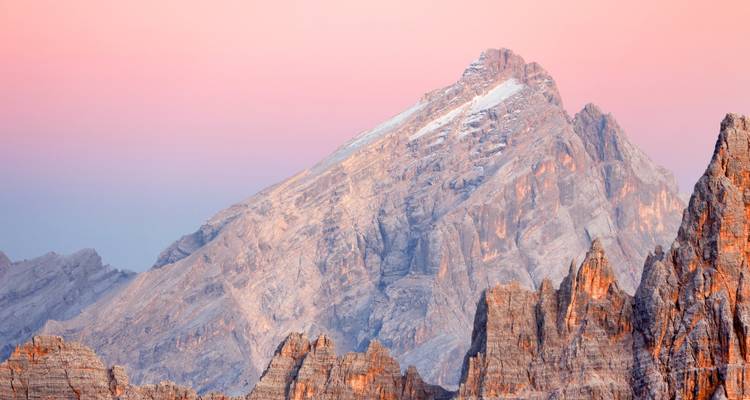 Mountains under a pink sky with rugged peaks at sunset.