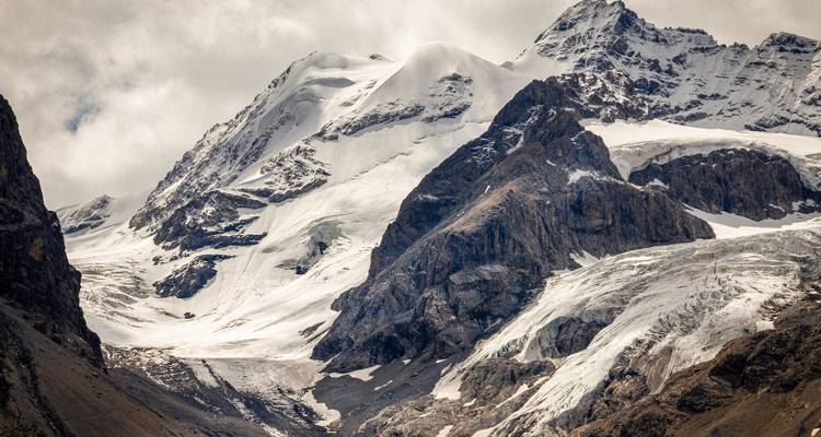 Picos montañosos cubiertos de nieve con un cielo dramático.