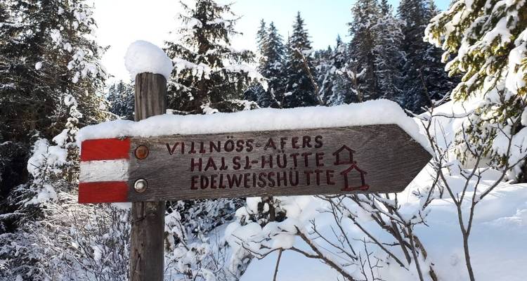 Panneau de sentier en bois couvert de neige.