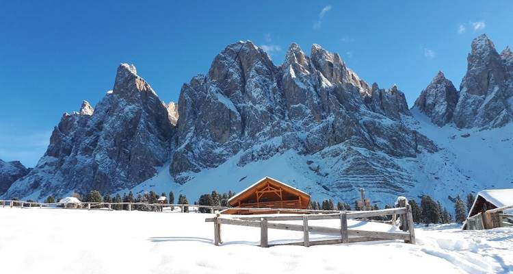 Montagnes enneigées avec un chalet en bois au premier plan.