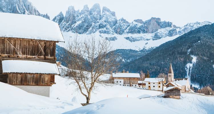Pueblo con casas cubiertas de nieve y picos montañosos.