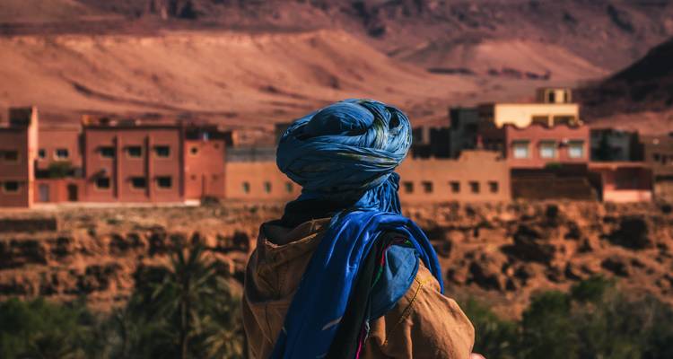 Persona en vestimenta tradicional mirando un pueblo del desierto.