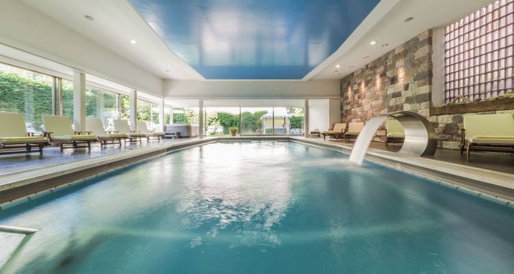 An indoor pool area with luxury seating and waterfall feature.