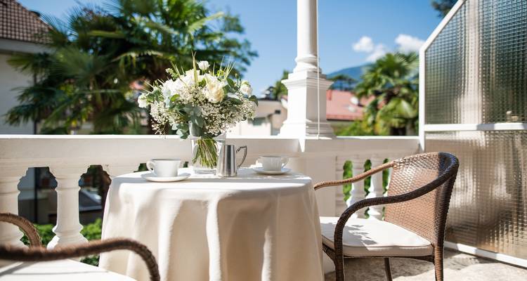 A cozy outdoor cafe setting with a flower arrangement and mountain view.