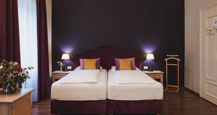Elegant hotel room interior with twin beds and soft lighting.