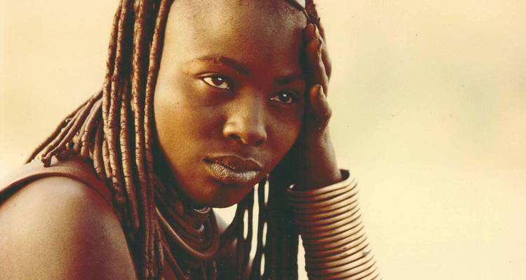 Ein Porträt einer Person mit geflochtenem Haar und traditionellem Schmuck.