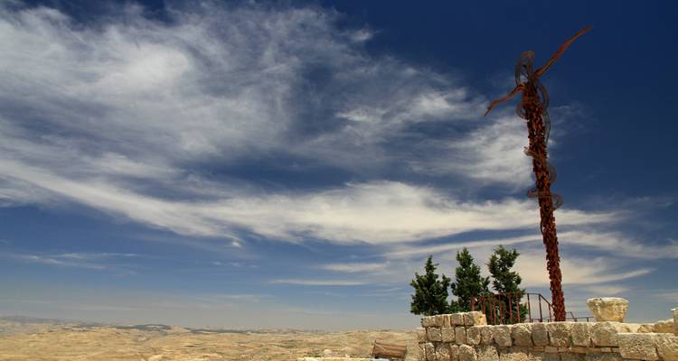 A scenic landscape with a cross sculpture and distant hills.