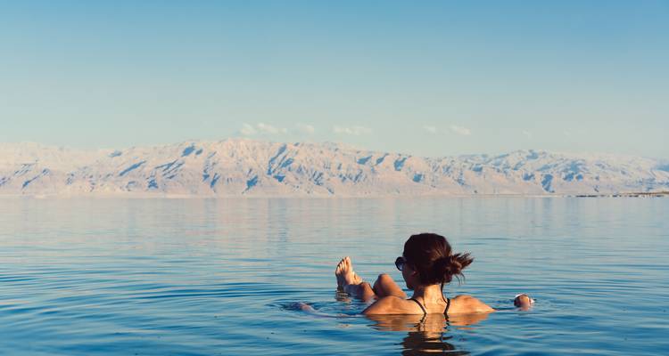 Person floating on the Dead Sea with mountainous background.