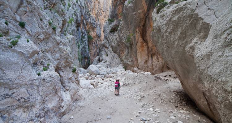 Smalle kloof met wandelaars, omringd door hoge rotsformaties.