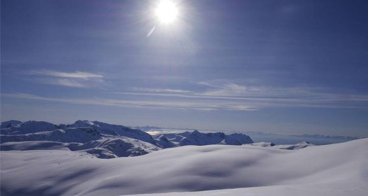 Vaste paysage montagneux enneigé sous un soleil éclatant.