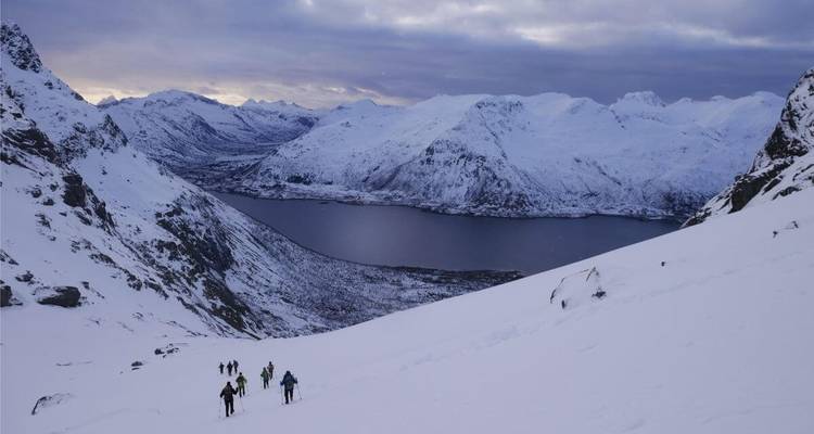 Gruppe von Skifahrern, die einen verschneiten Berg hinaufsteigen.