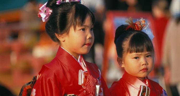 Zwei Kinder in traditioneller Kleidung besuchen ein Festival.