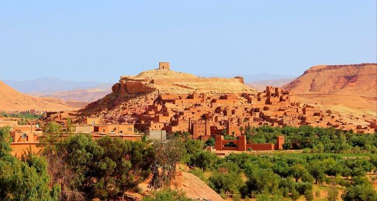 Altes befestigtes Dorf auf einem Hügel, umgeben von Grün.