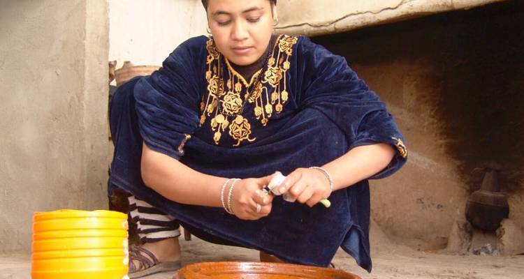 Frau in traditioneller Kleidung bereitet Essen zu.