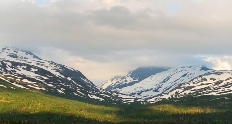 Snow-capped mountain range under a partly cloudy sky.