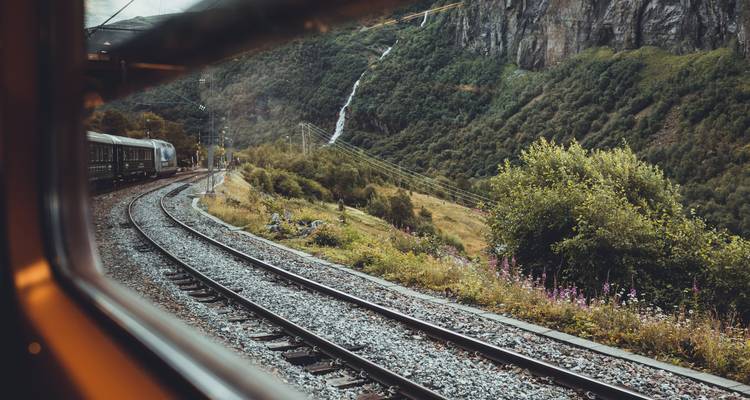 Scenic landscape viewed from a train window with mountains and railway.
