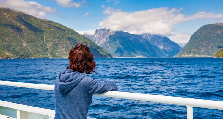 Person, die von einem Boot aus über einen Fjord blickt.
