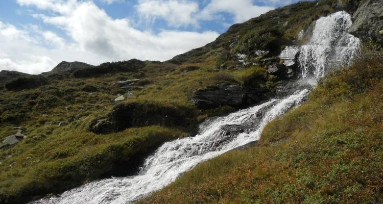 Waterfall cascading down a rocky slope with greenery around.