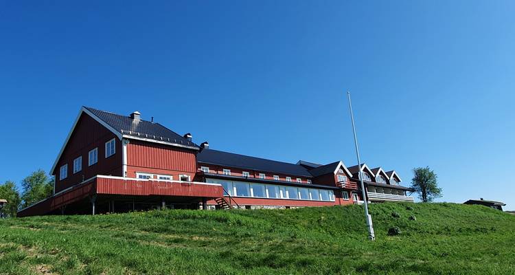 Traditionelles rotes Gebäude auf einem üppigen grünen Hügel.