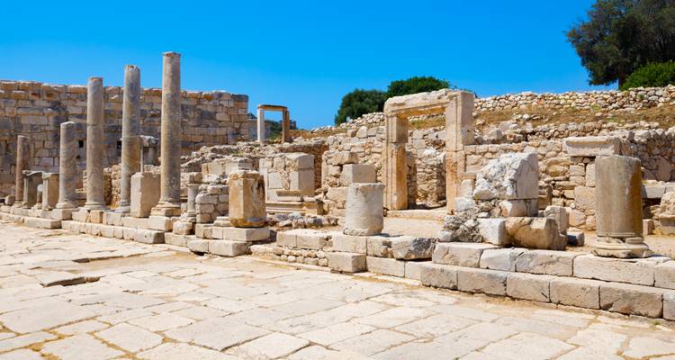 Ruins of ancient stone columns and walls under a clear blue sky.