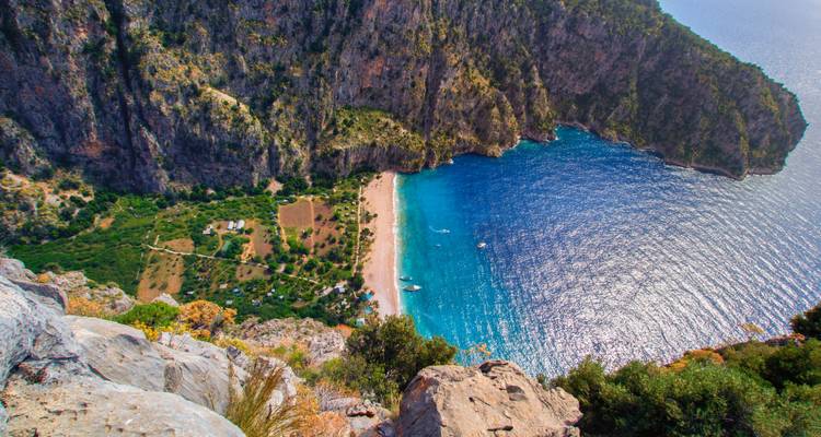 Aerial view of a secluded beach with blue waters surrounded by cliffs.