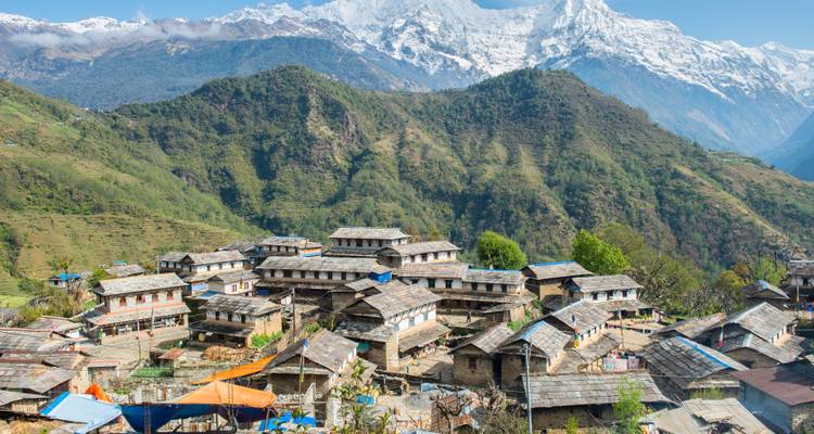 Bergdorp genesteld tussen terrasvelden met besneeuwde bergen.