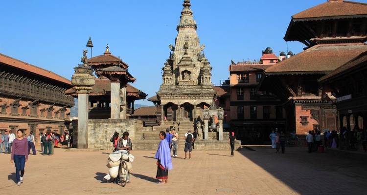 Oud plein met historische gebouwen en wandelende mensen.