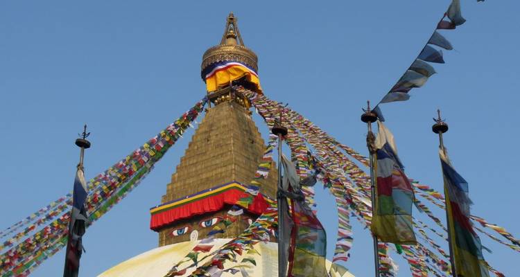 Stupa met kleurrijke gebedsvlaggen tegen een helderblauwe hemel.
