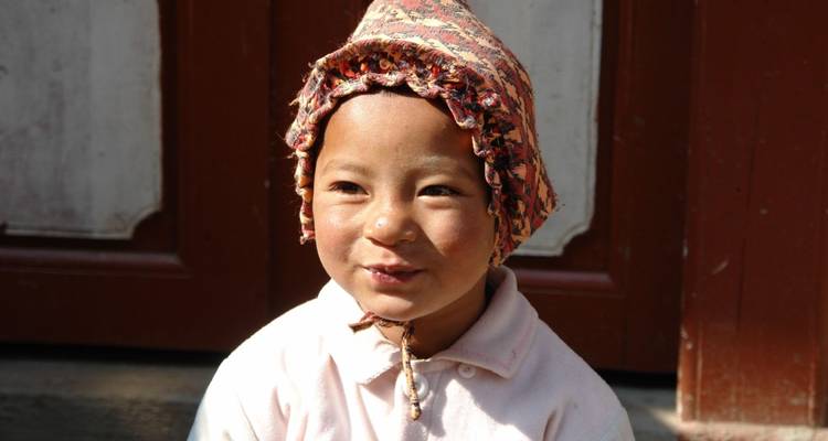 Jong kind lachend buiten met een zonnehoed.