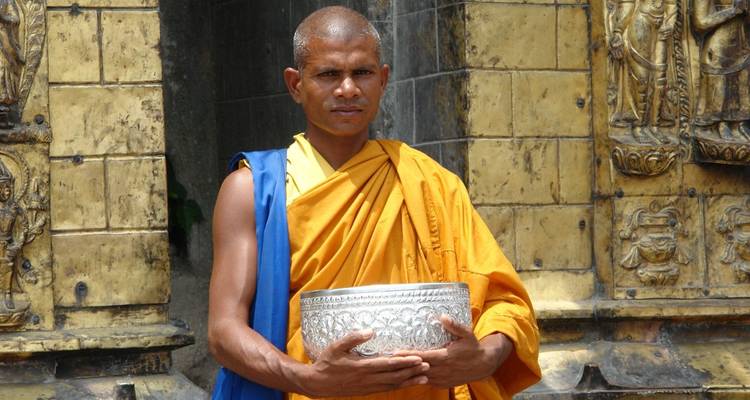 Monnik in levendige gewaden met een kom in zijn handen.