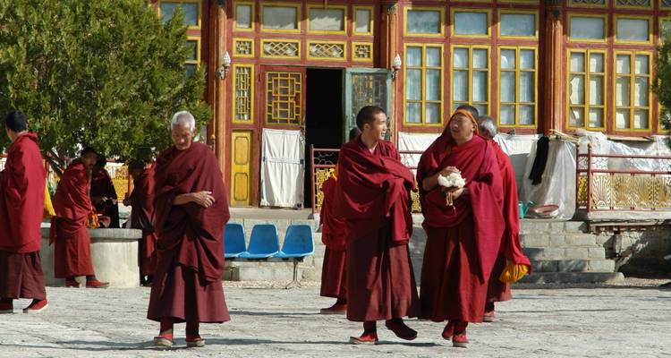 Groep monniken in rode gewaden lopend op een tempelplein.
