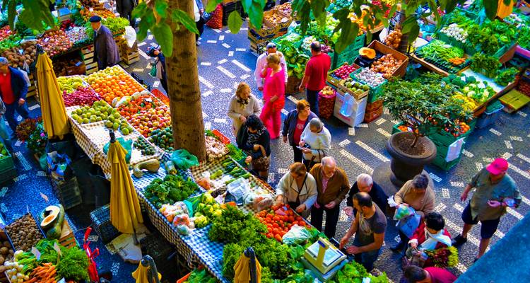 Bullicioso mercado cubierto de frutas y verduras con puestos coloridos de frutas y verduras visto desde arriba.