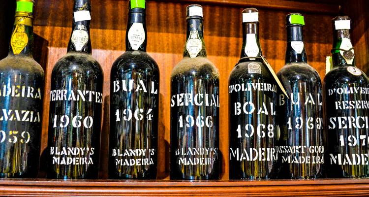 Botellas vintage de vino de Madeira alineadas en estantes de madera.